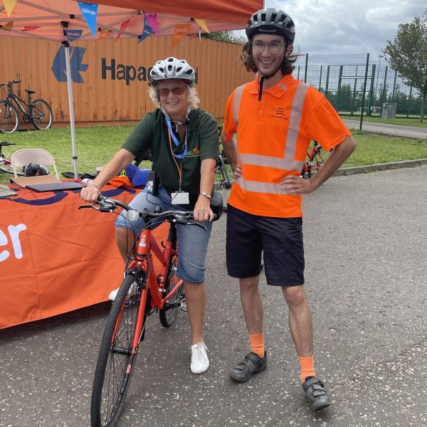 Lorraine smiling on her bike with a man in high viz.